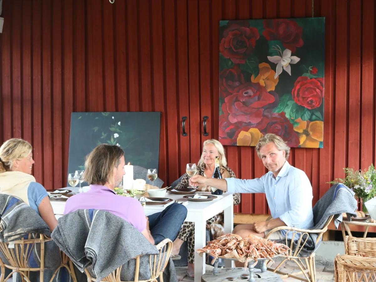 Vänner samlade kring ett dukat bord i den röda ladan