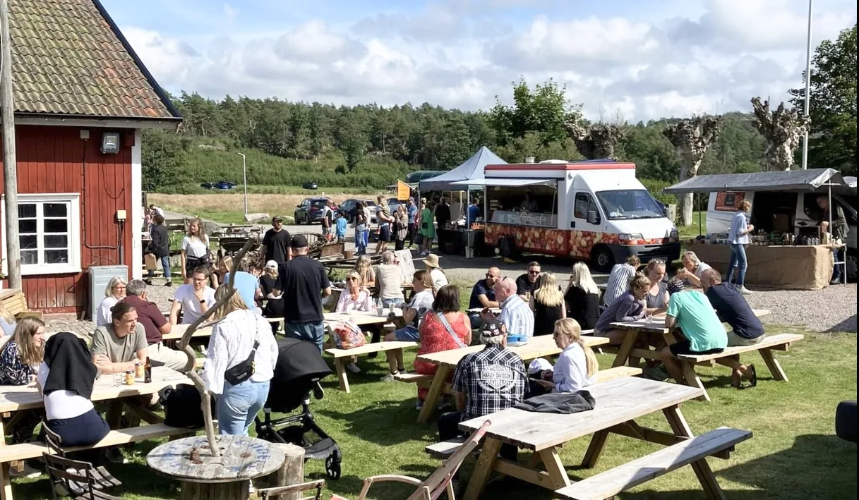Besökare samlas kring långbord och marknadsstånd på gårdsplanen