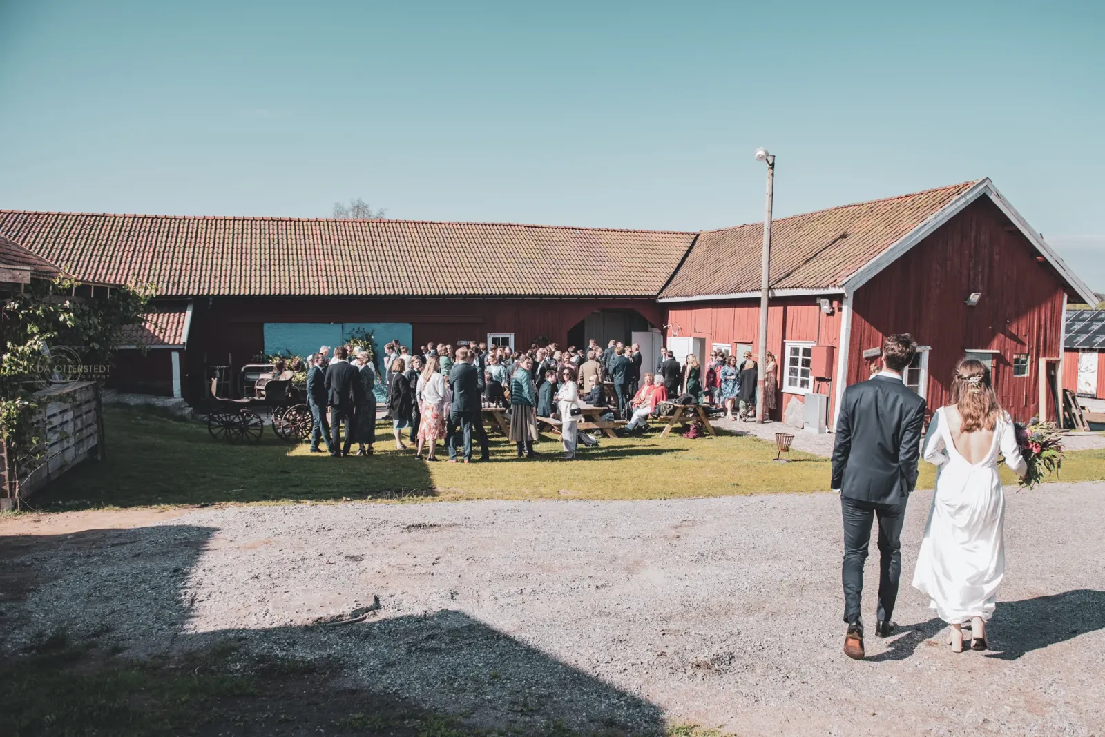 Brudpar på väg in mot gästerna på gårdsplanen